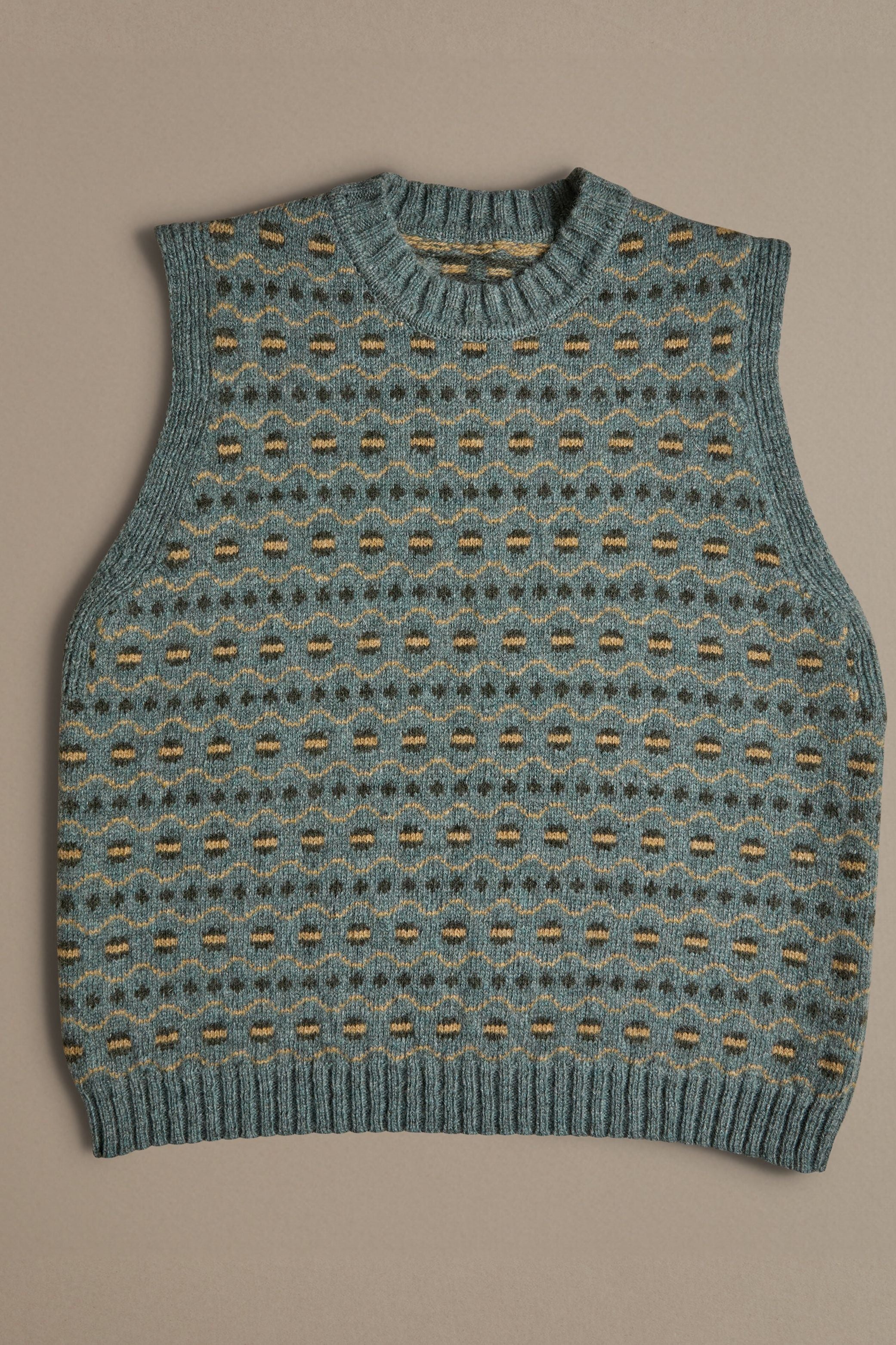 A blue vest with a Fair Isle pattern. Knitted in Scottish spun wool, designed and made in the UK. 